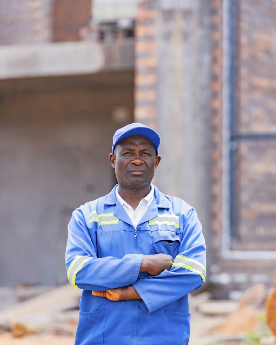 A technician in a blue uniform, arms crossed, ready for the next job.