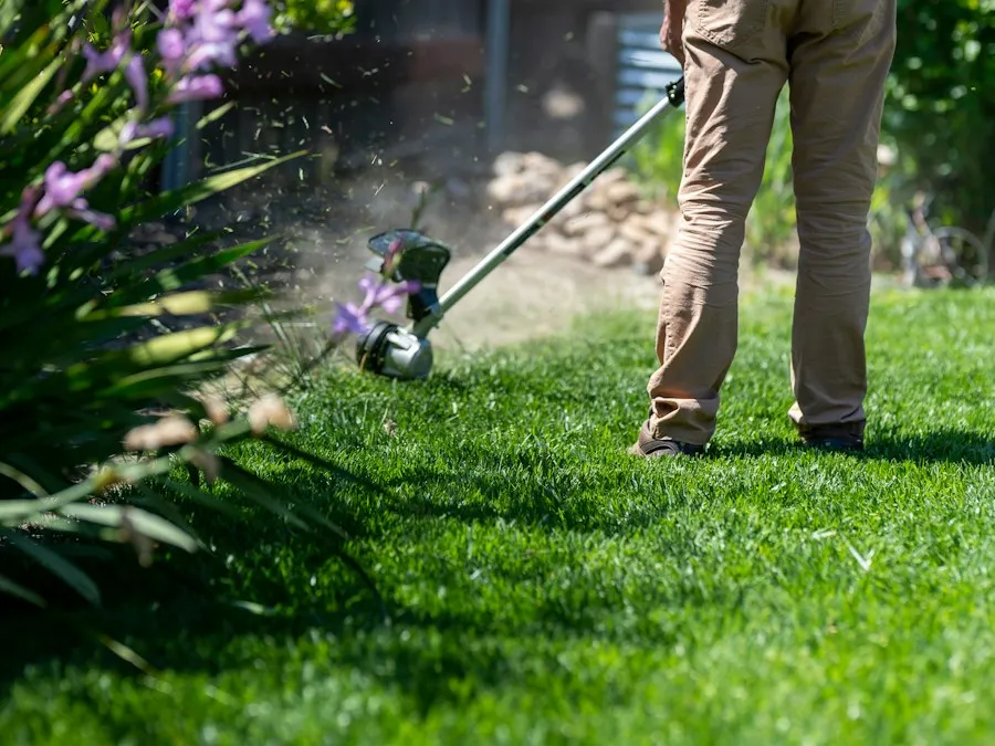 A landscaper edging a bed with a string trimmer.